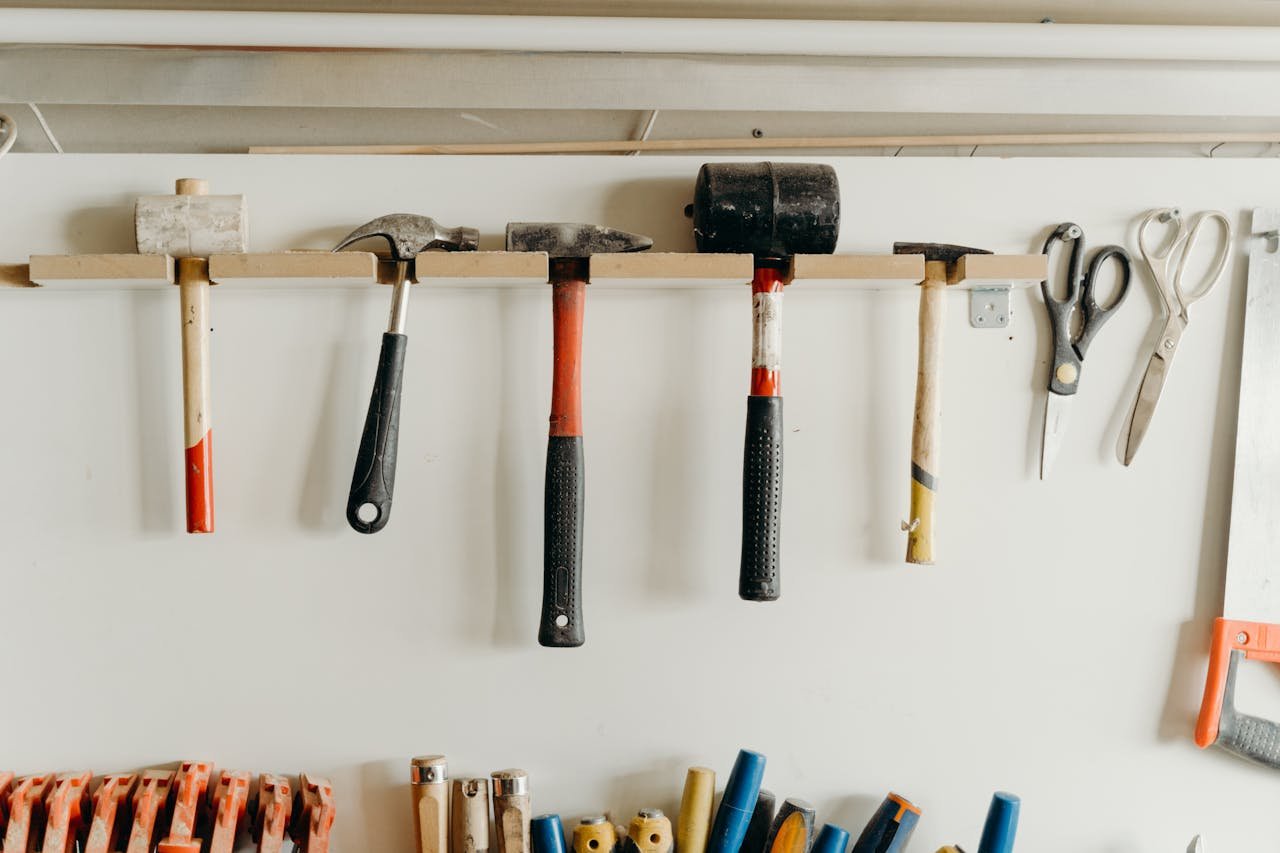 Home Neatly organized tools hanging on a workshop wall, including hammers and scissors.